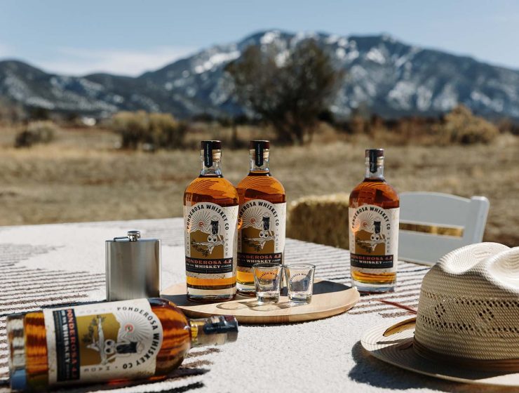 NM Whiskey Ponderosa Whiskey bottles on table horizontal mountains credit Amanda Powell