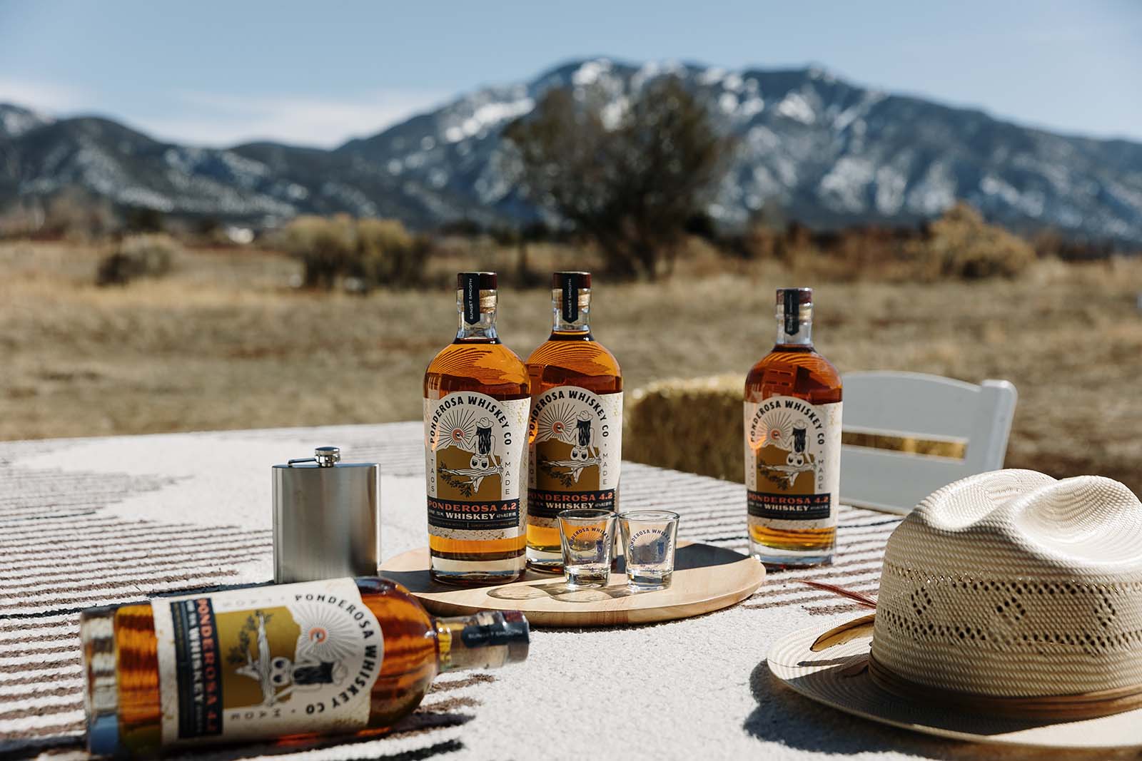 NM Whiskey Ponderosa Whiskey bottles on table horizontal mountains credit Amanda Powell